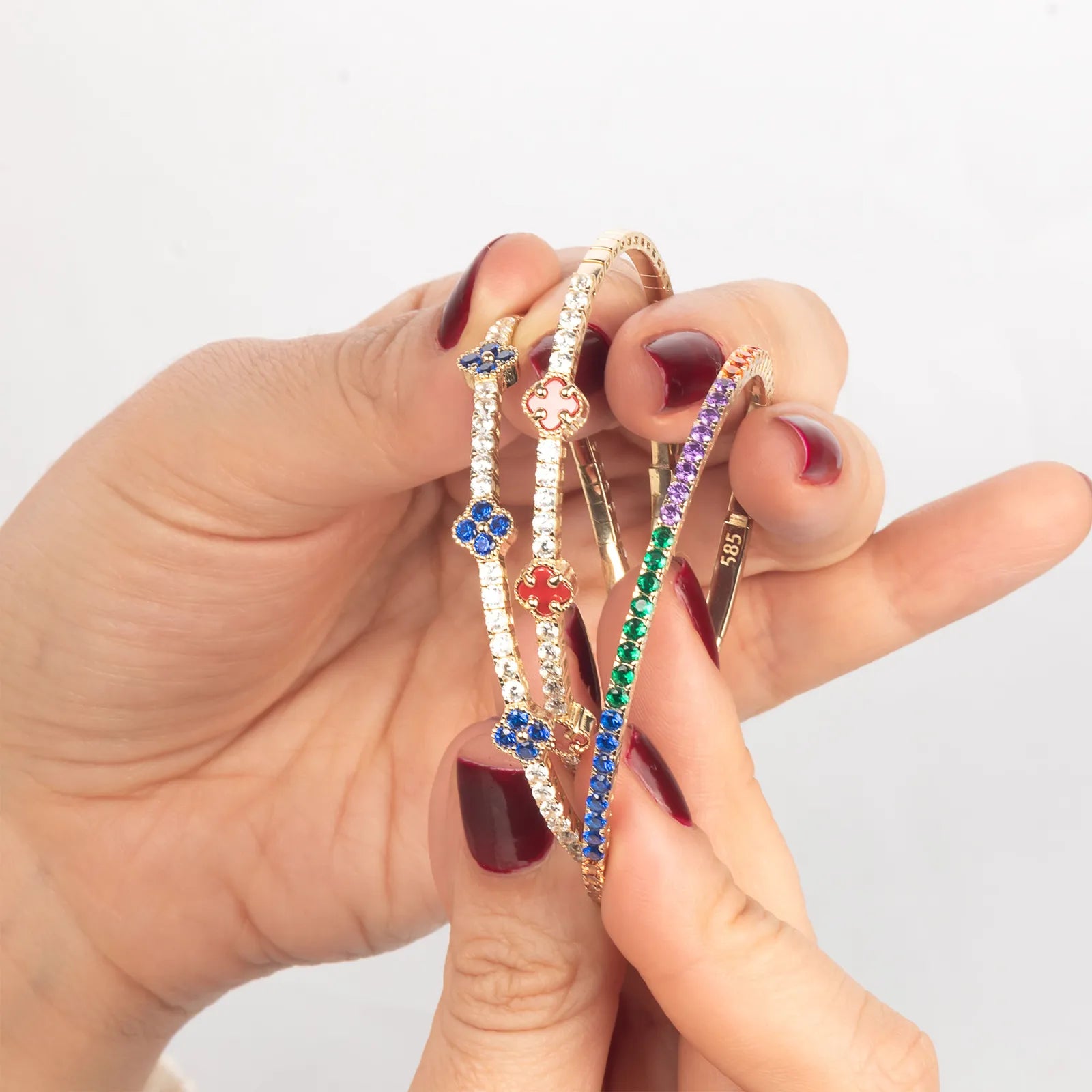 A handcrafted gold bracelet featuring delicate multi-colored enamel clover charms with diamond accents, designed for a sophisticated statement look.