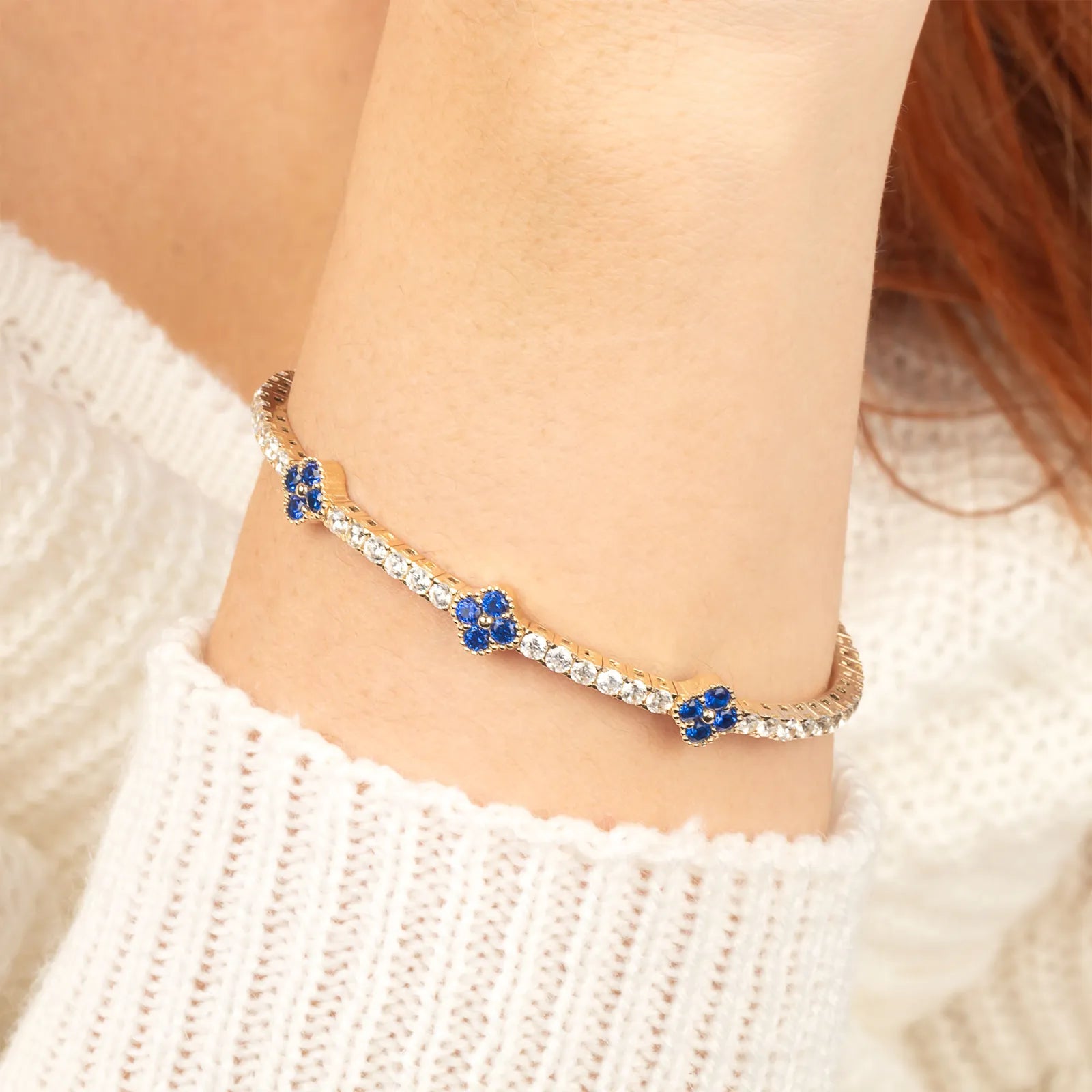 A delicate 14K gold bangle bracelet with sparkling moissanite and blue sapphire flower charms, offering a timeless and sophisticated look.