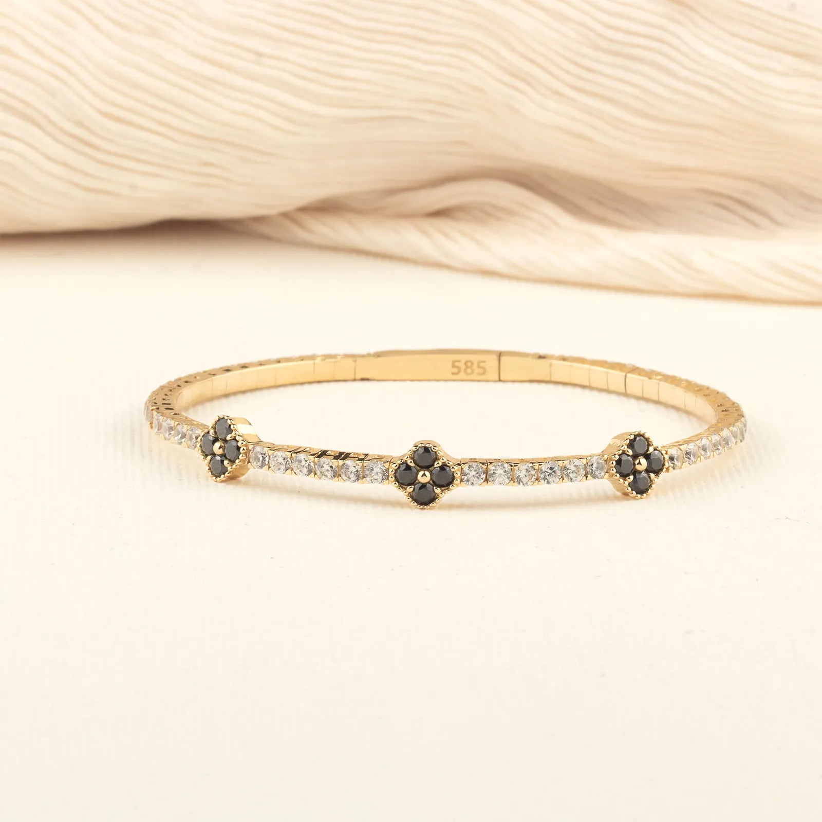 A beautifully handcrafted black onyx clover bracelet with a minimalist gold design, worn as a statement piece.