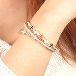 A vibrant stack of enamel clover and diamond tennis bracelets in gold, featuring playful pastel and bold colors for a unique and trendy look.