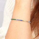 A delicate and flexible 14K gold rainbow gemstone bracelet, adding a subtle yet striking pop of color to any outfit.