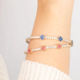 Dainty and flexible 14K gold bangle featuring blue sapphire gemstone flowers, ideal for everyday wear or special occasions.