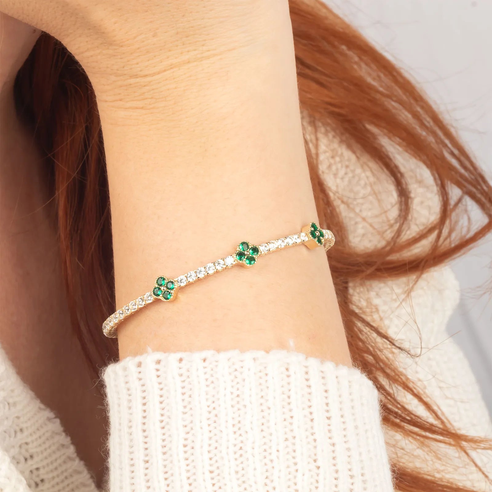 A delicate 14K gold bracelet adorned with ruby gemstone clover motifs and moissanite accents, designed for timeless elegance.