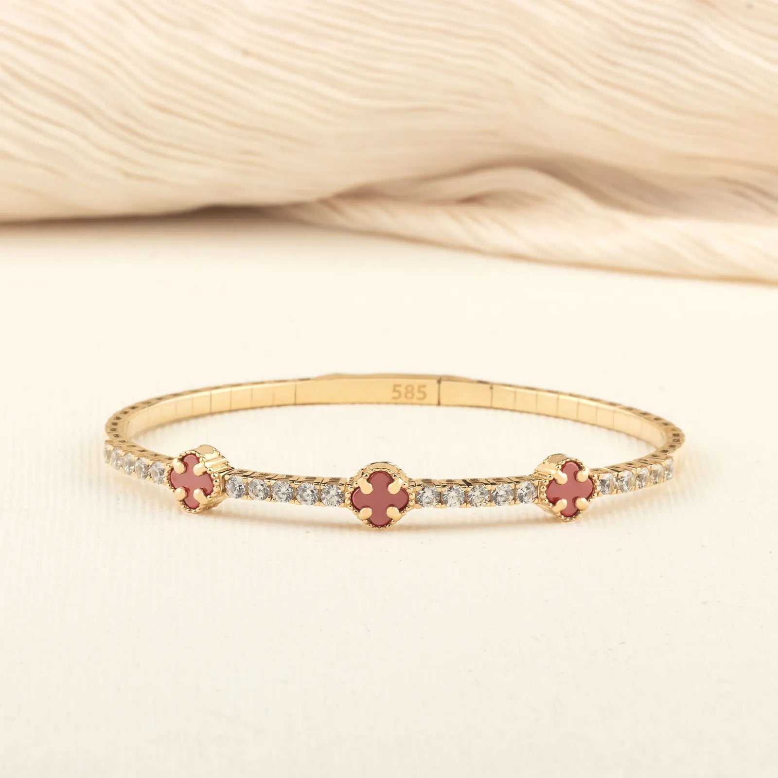 a close-up of a 14K gold tennis bracelet featuring colorful clover-shaped enamel charms and diamond accents, perfect for sophisticated styling."