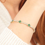A handcrafted 14K gold bracelet with vibrant green gemstone clover motifs and diamond accents, blending classic elegance with modern style."