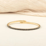 A sophisticated gold tennis bracelet encrusted with black diamonds, offering a classic yet modern touch to any outfit.