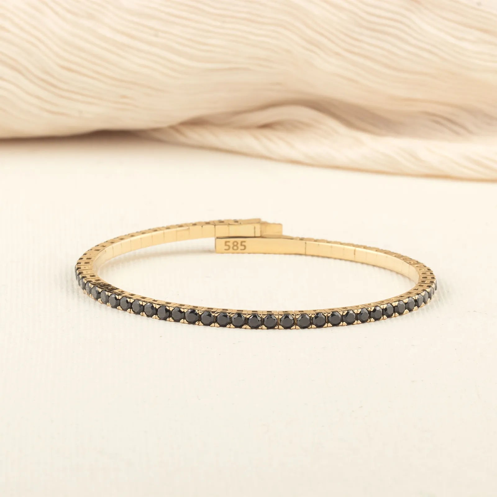 A sophisticated gold tennis bracelet encrusted with black diamonds, offering a classic yet modern touch to any outfit.