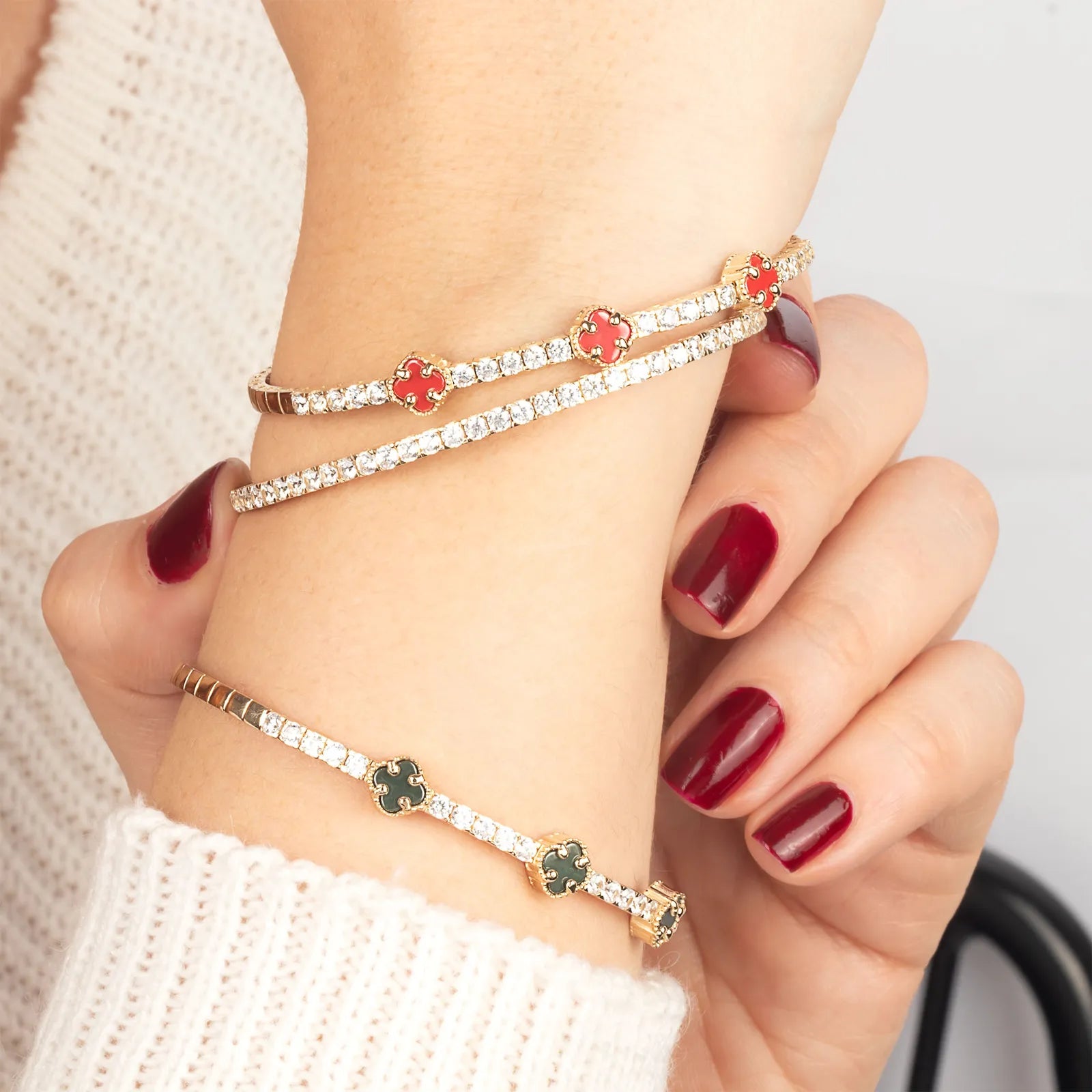 An elegant 14K gold bracelet adorned with white and red enamel clover charms, beautifully set with sparkling gemstones for a luxurious finish.