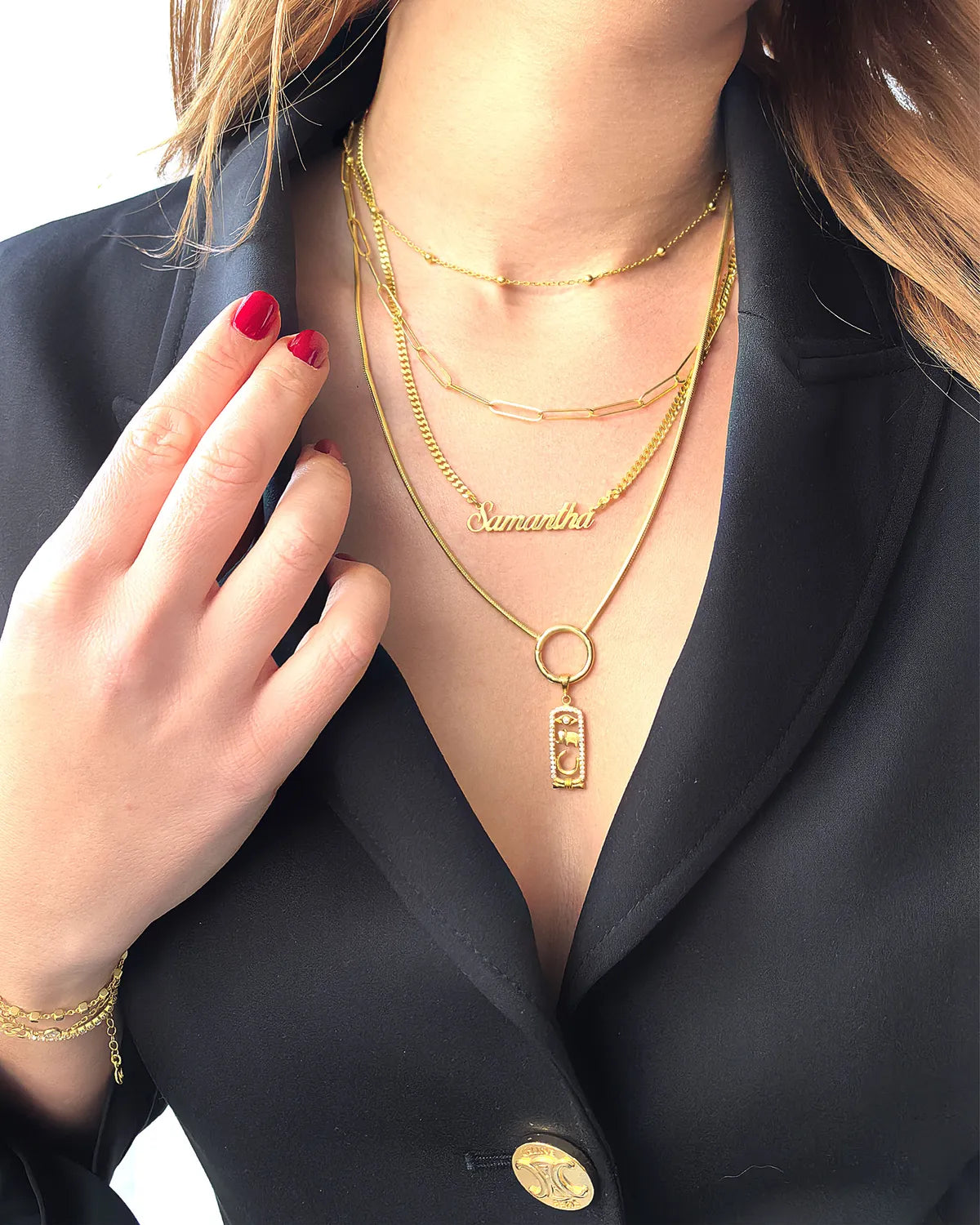 Close-up of a woman wearing layered gold necklaces, including a personalized name necklace and a charm pendant on a sleek gold chain. Elegant fine jewelry from MyJewelist, perfect for stacking and styling.