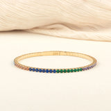A sleek and elegant Original Name Necklace 14K gold bangle adorned with colorful gemstones, arranged in a beautiful gradient.