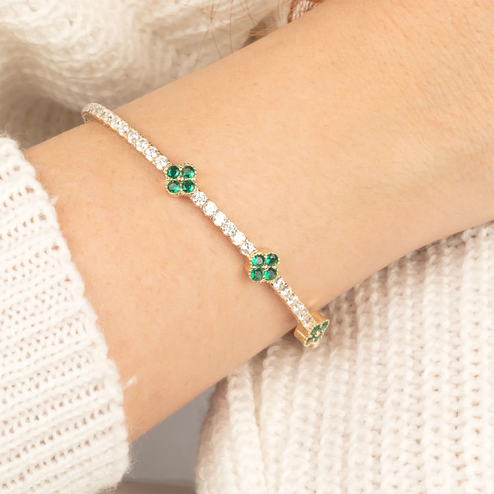 An elegant and timeless 14K gold bracelet adorned with green gemstone clover charms and brilliant diamonds, offering effortless sophistication.