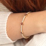 A handcrafted 14K gold bracelet featuring brilliant-cut garnet crystals and dazzling moissanite, perfect for everyday elegance.