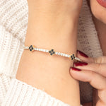 A stylish black onyx and gold bangle bracelet, elegantly worn on a woman's wrist, showcasing its flexible fit.