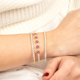 A woman's wrist adorned with gold moissanite and ruby tennis bracelets, blending elegance with vibrant gemstone details.