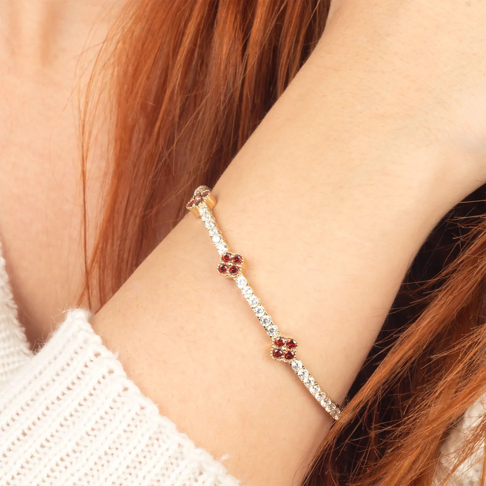 A luxurious 14K gold flexible clover bracelet featuring deep red ruby stones and sparkling moissanite diamonds, perfect for elegant women’s jewelry.