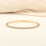 A delicate gold diamond tennis bracelet elegantly displayed on a soft beige fabric, emphasizing its timeless design and premium craftsmanship.