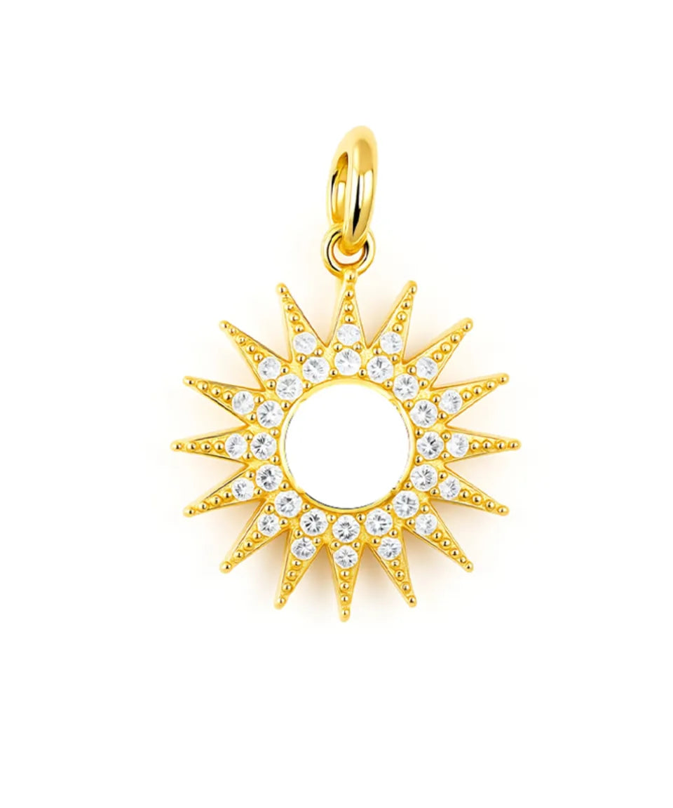 Gold sun-shaped pendant with clear stones on a white background