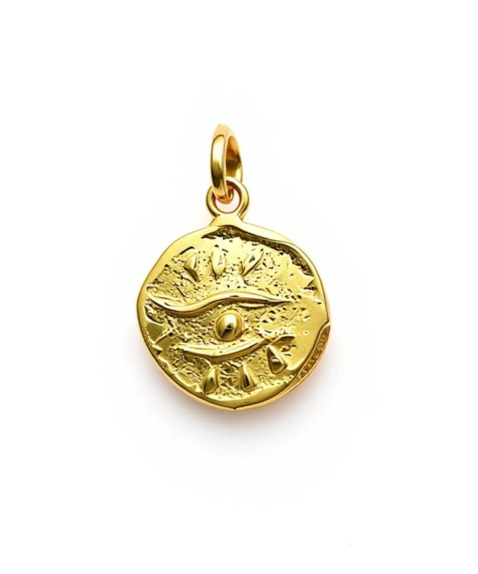 Gold pendant with eye design on a white background