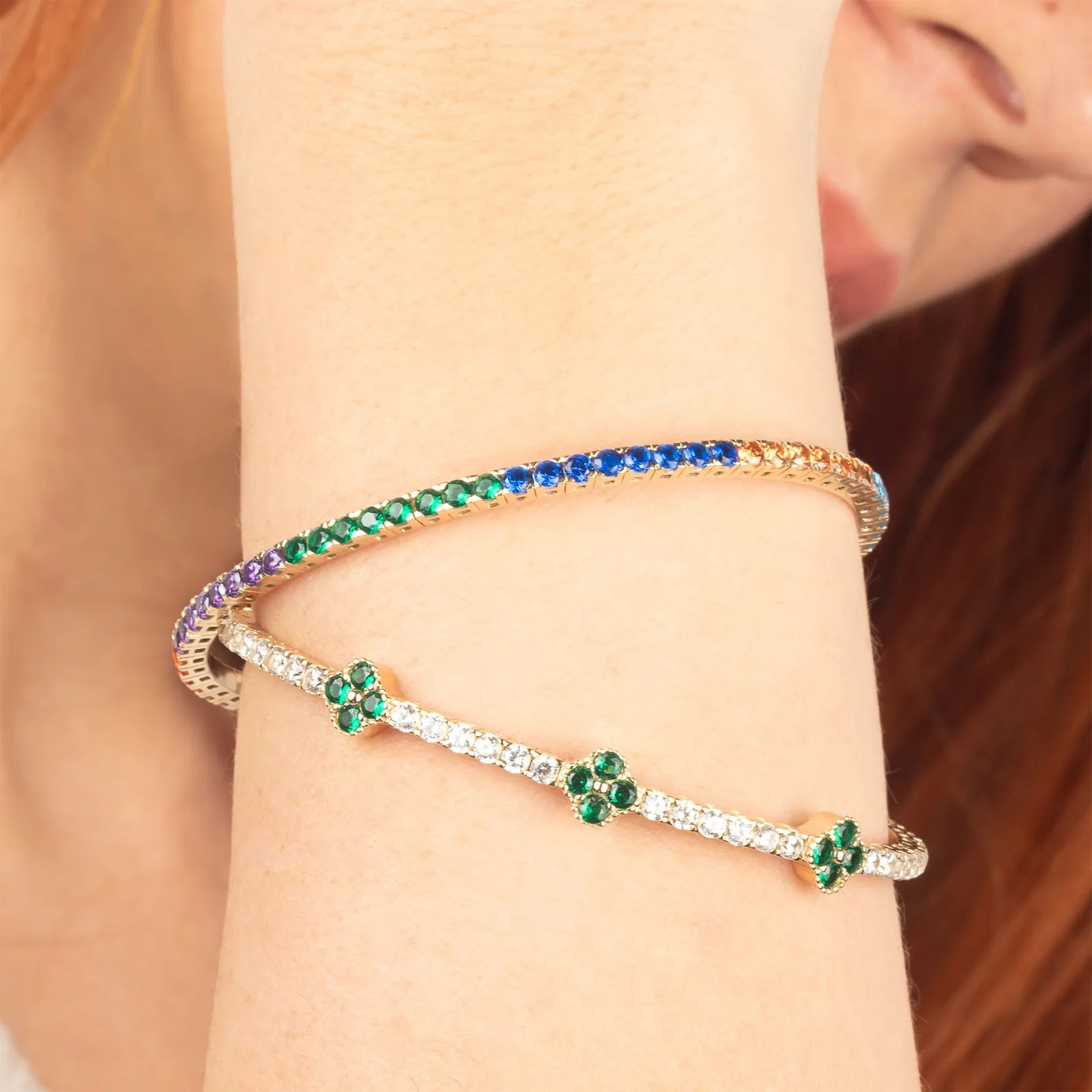 A graceful 14K gold bracelet featuring sparkling emerald and white stones in a delicate clover design, ideal for stacking or wearing alone."
