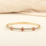 a  close-up of a 14K gold tennis bracelet featuring colorful clover-shaped enamel charms and diamond accents, perfect for sophisticated styling."
