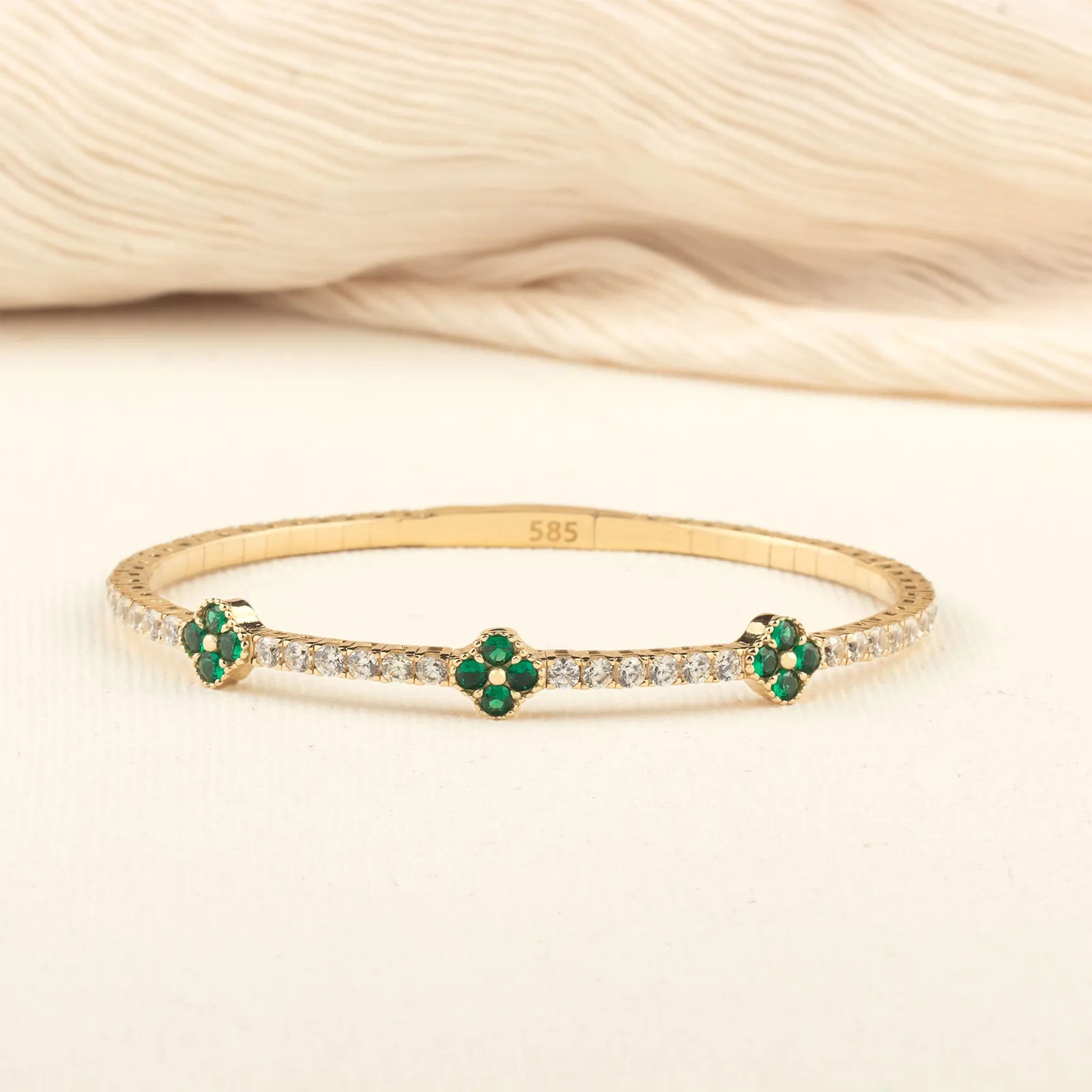 A delicate and refined 14K gold bracelet with emerald-green clover motifs, designed to add a luxurious touch to any jewelry collection.