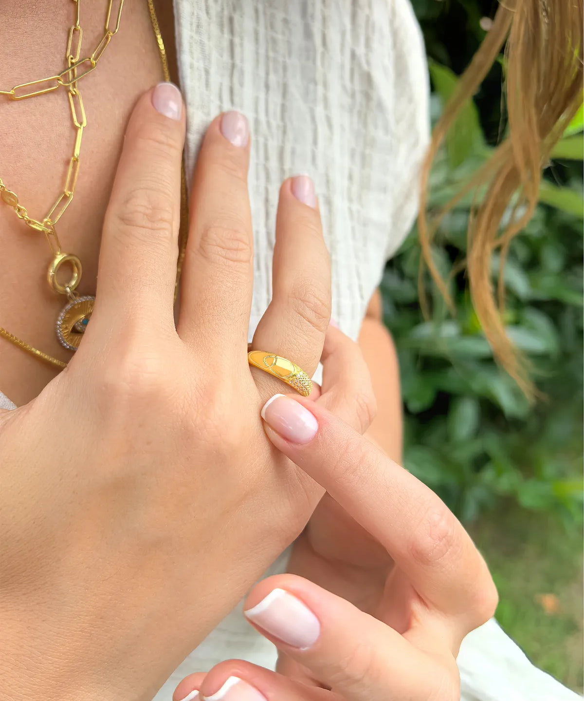 Close-up of a hand wearing a gold ring with a blurred green background.| MyJewelist