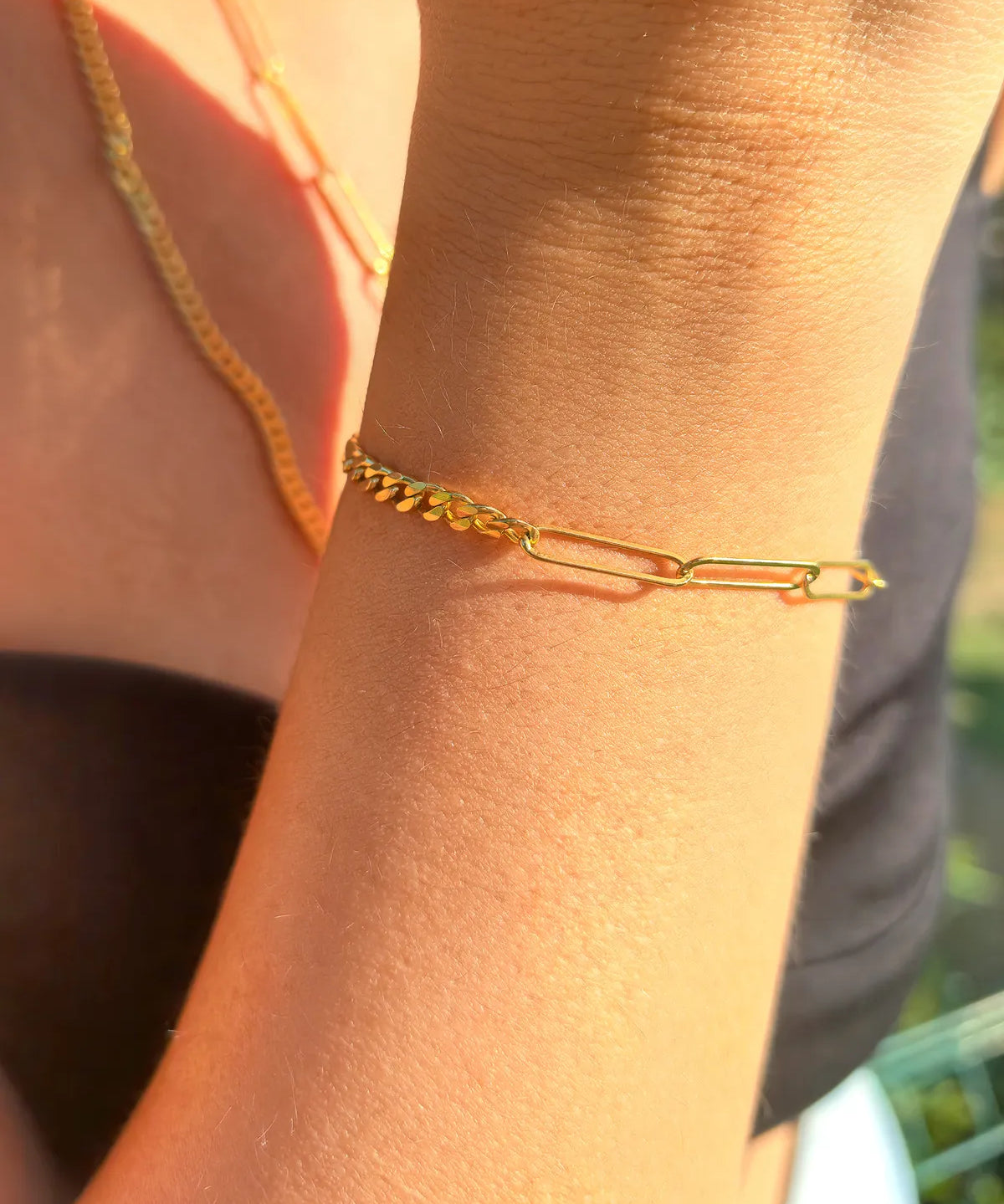 Gold chain bracelet on a wrist with a blurred background