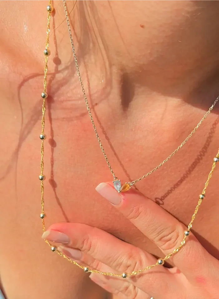 Close-up of a gold necklace with a small pendant on a person's neck.