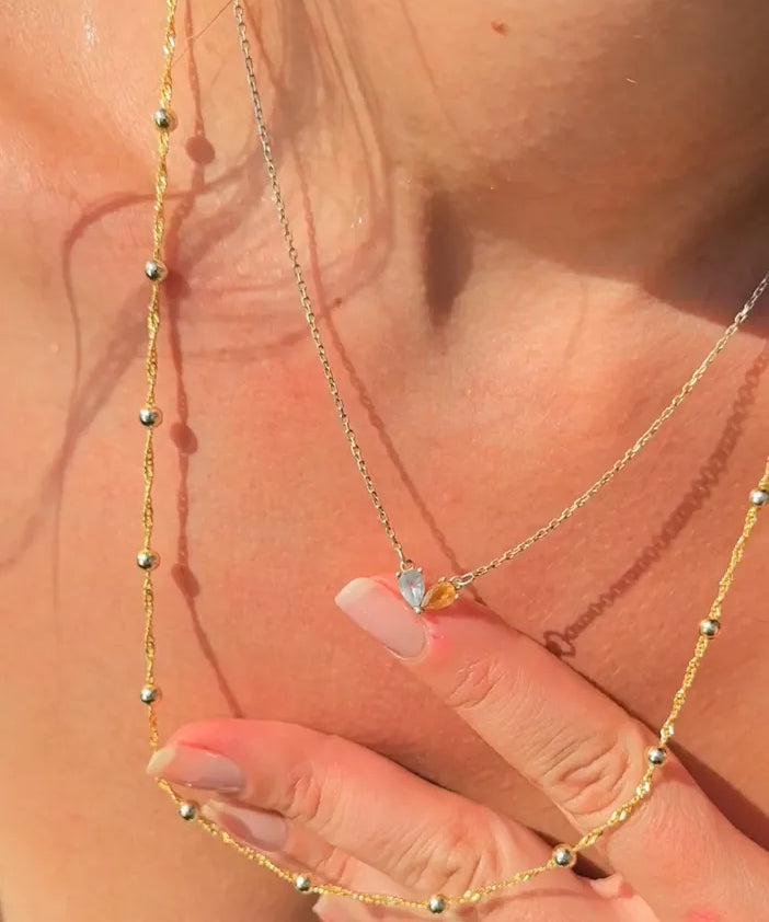 Close-up of a gold necklace with a small pendant on a person's neck.