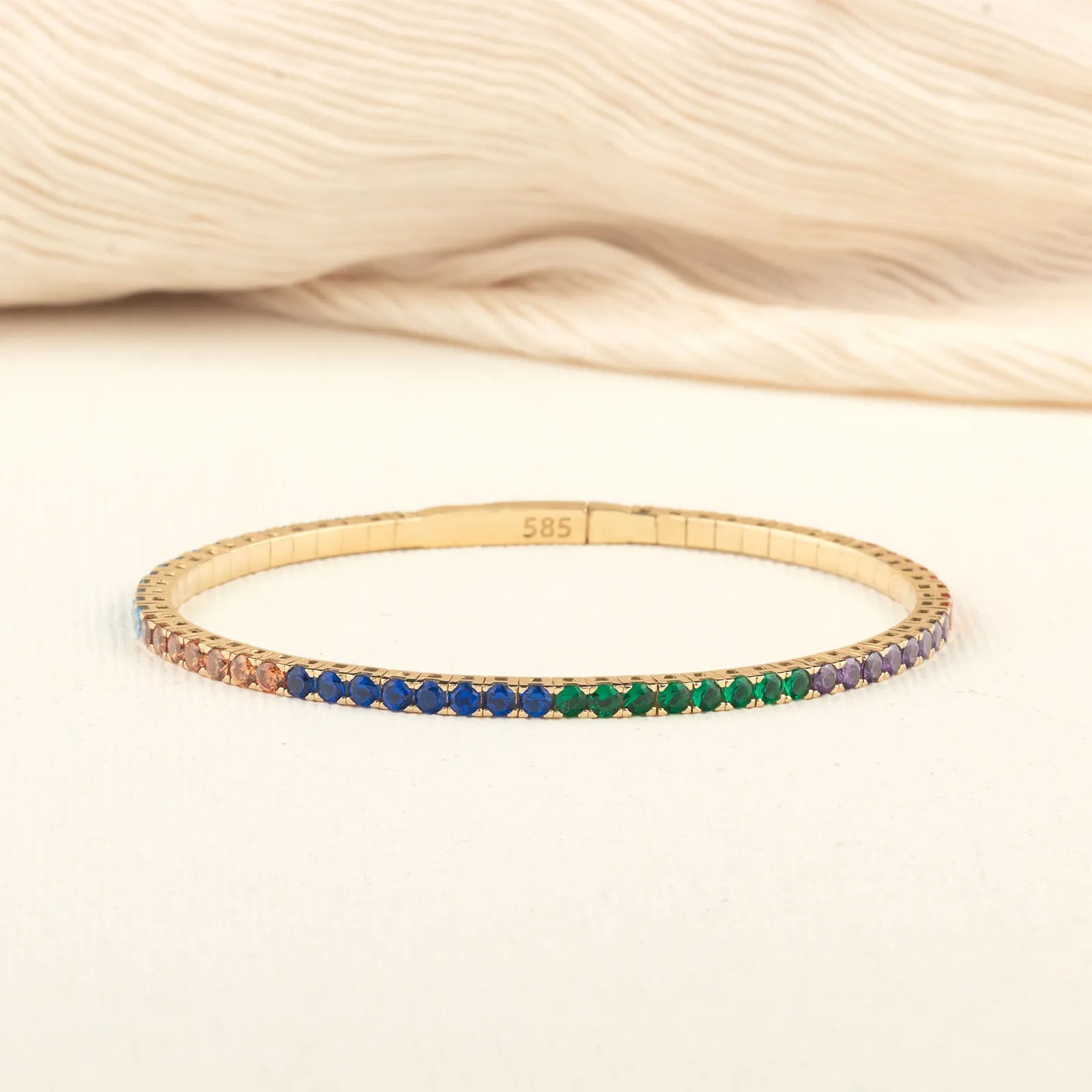  A sleek and elegant Original Name Necklace 14K gold bangle adorned with colorful gemstones, arranged in a beautiful gradient.