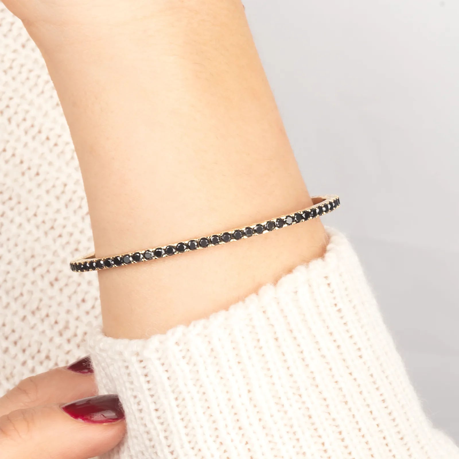 Close-up of a luxurious 14K gold bracelet adorned with black diamonds, perfect for sophisticated styling and special occasions."