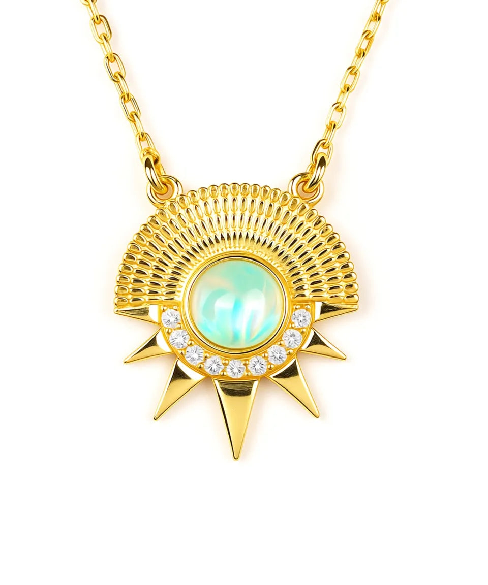 Gold necklace with a sun-shaped pendant featuring a green gemstone and small diamonds on a white background