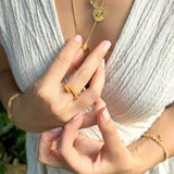 Close-up of hands wearing gold jewelry with a blurred natural background