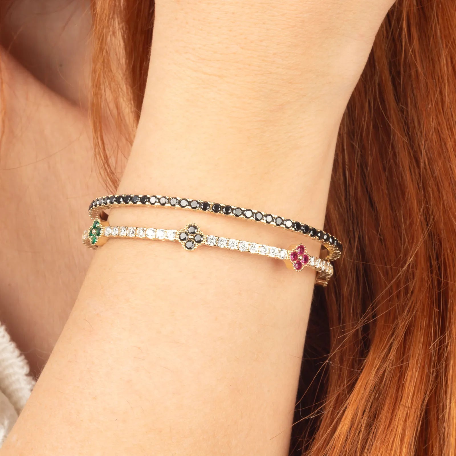 Close-up of a wrist with three bracelets on a neutral background.| MyJewelist